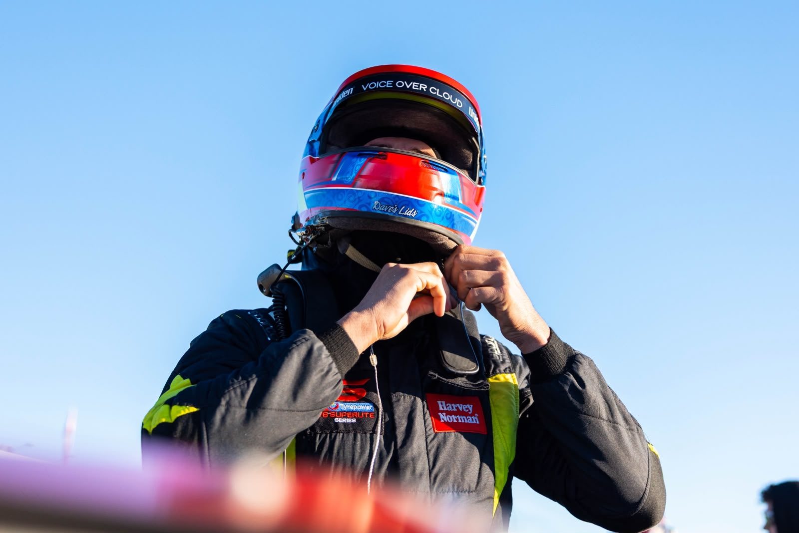 Jack Westbury fastening his race helmet, with Voice Over Cloud across the visor strip